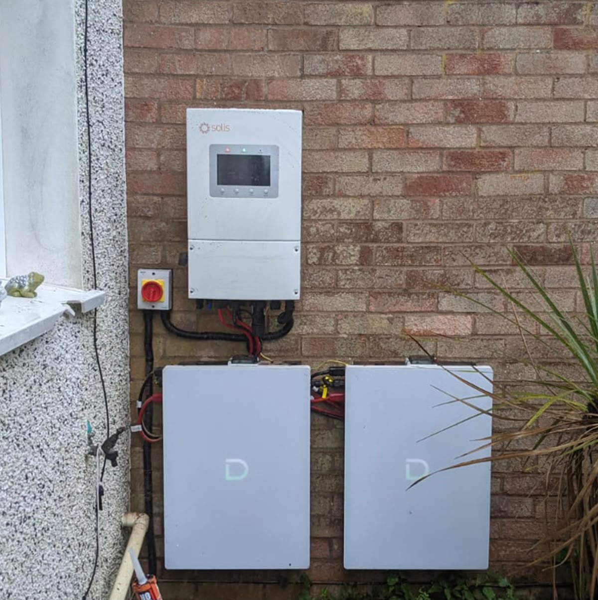 Solis inverter with two stacked home battery units on a brick wall